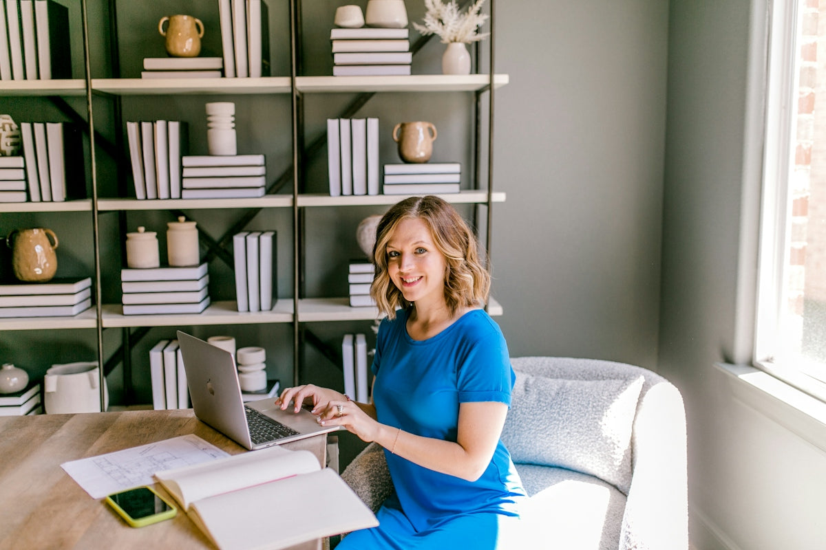 Smiling woman working on laptop at a desk.