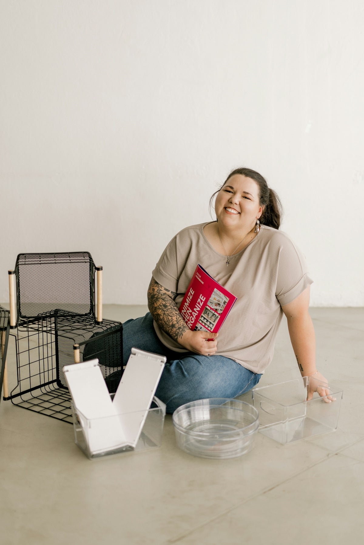 Smiling woman on floor with storage items and a book.